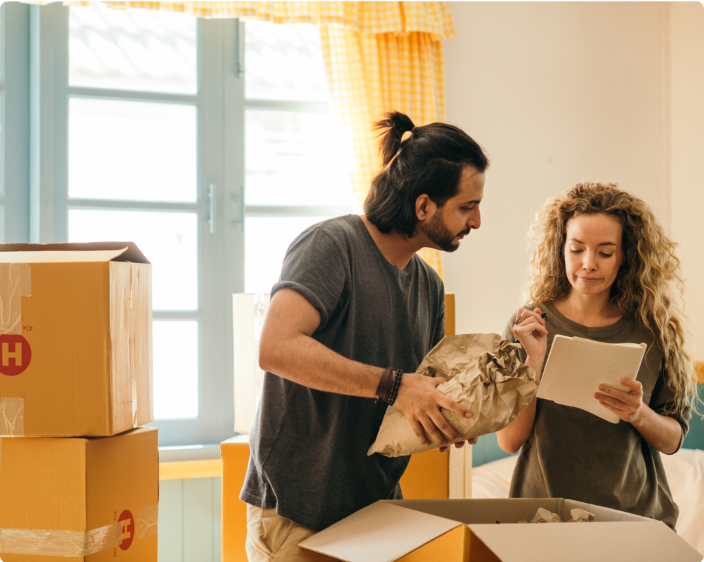 Hombre y mujer empaquetando sus pertenencias y revisando su contrato de alquiler.